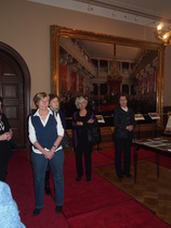 Klubilaiset kokoontuneena kuuntelemaan opastusta. Taustalla suuri maalaus, joka esittää Maapäivien avajaisia vuonna 1863